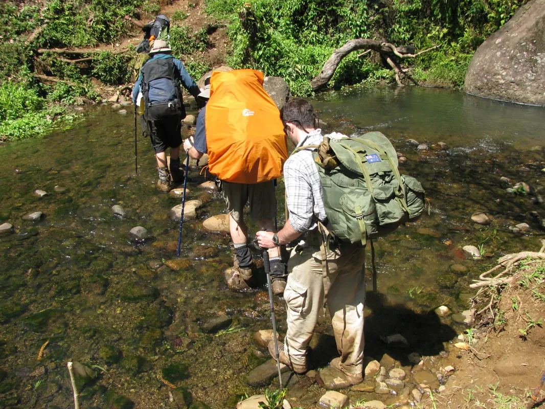 Trekkers wading a creek with packs